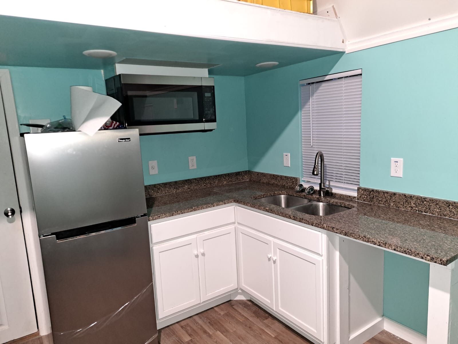 Tiny home kitchen with granite countertops, stainless steel appliances, and white cabinetry