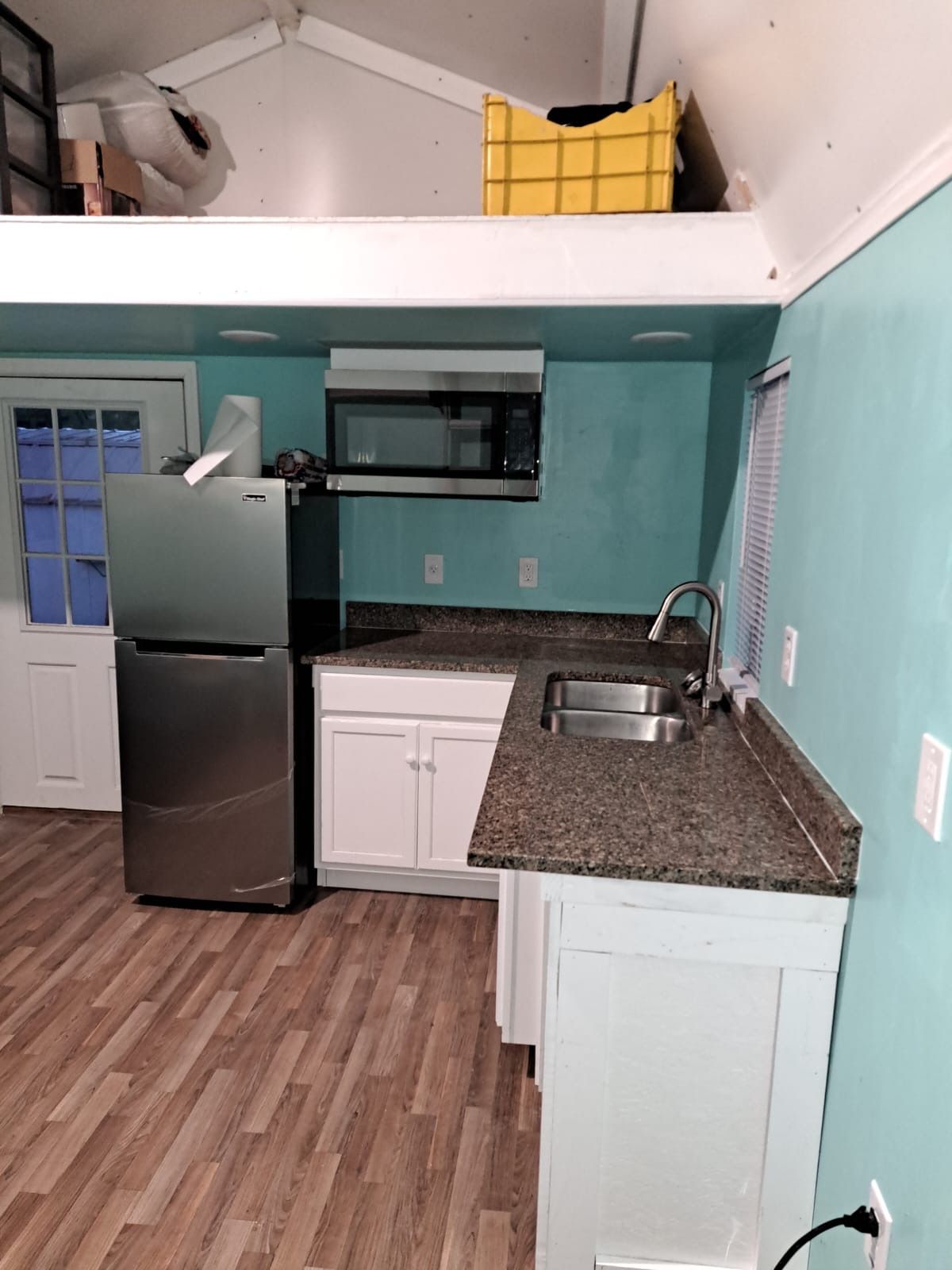 Tiny home interior showing kitchen and sleeping loft with vaulted ceiling