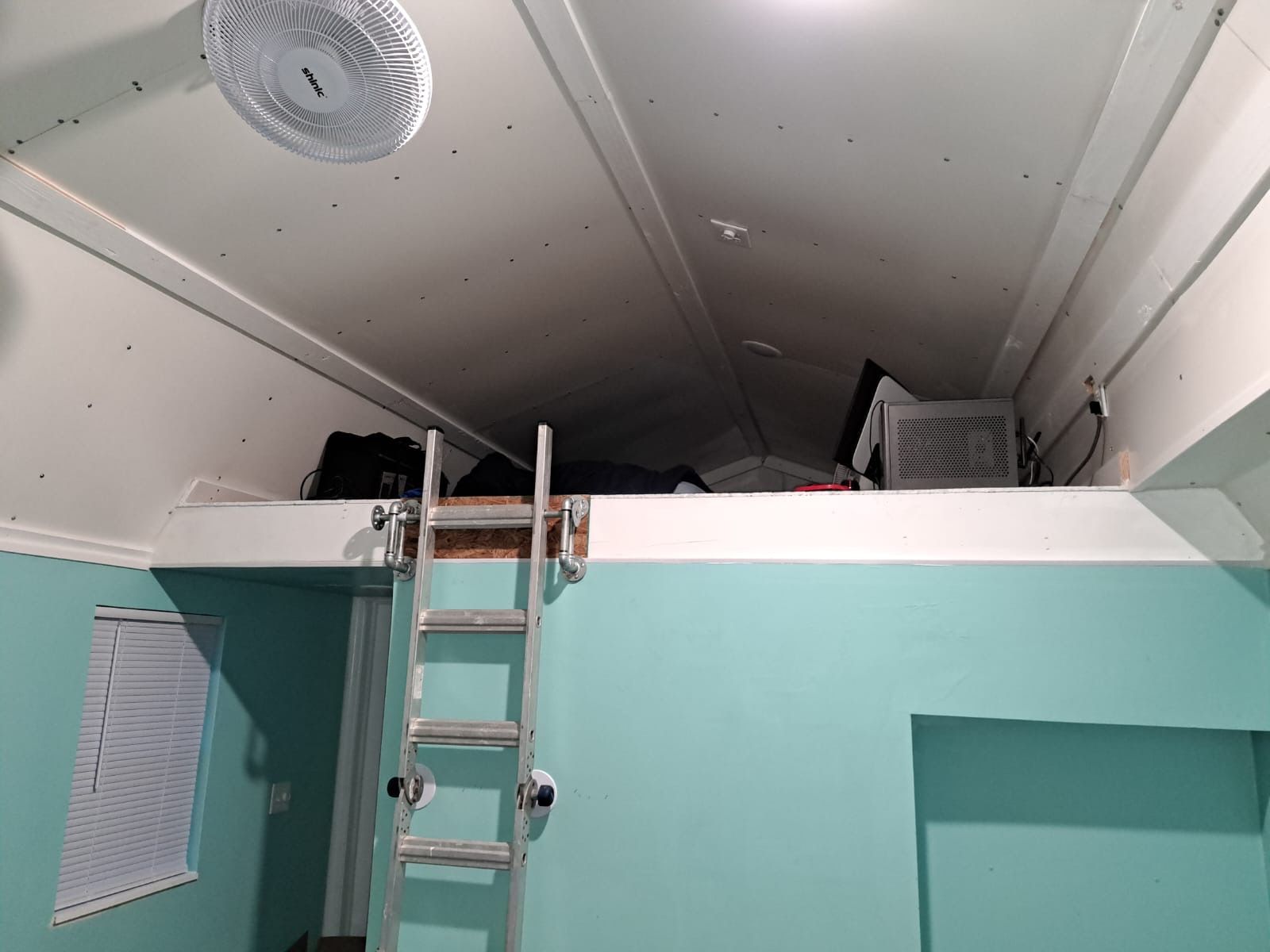 Tiny home loft with custom industrial ladder rail and recessed lighting