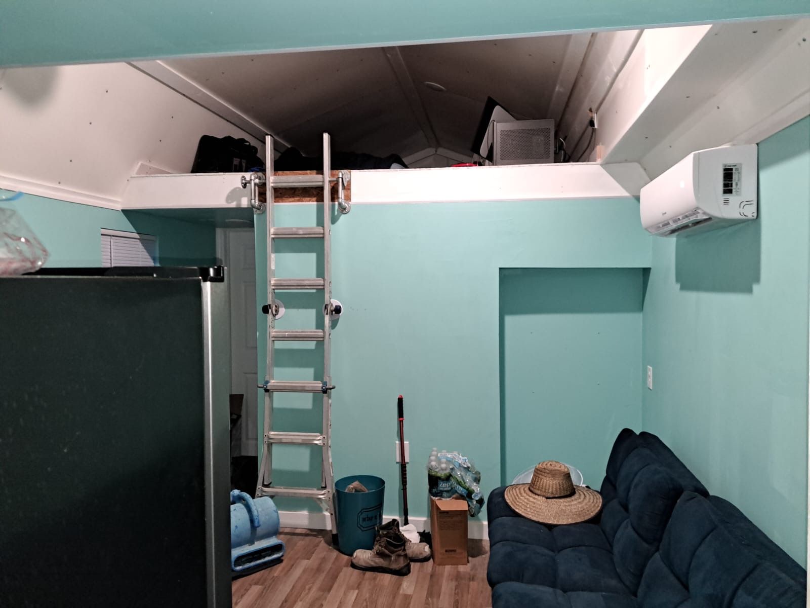 Tiny home living area with mini-split AC, loft access, and seating